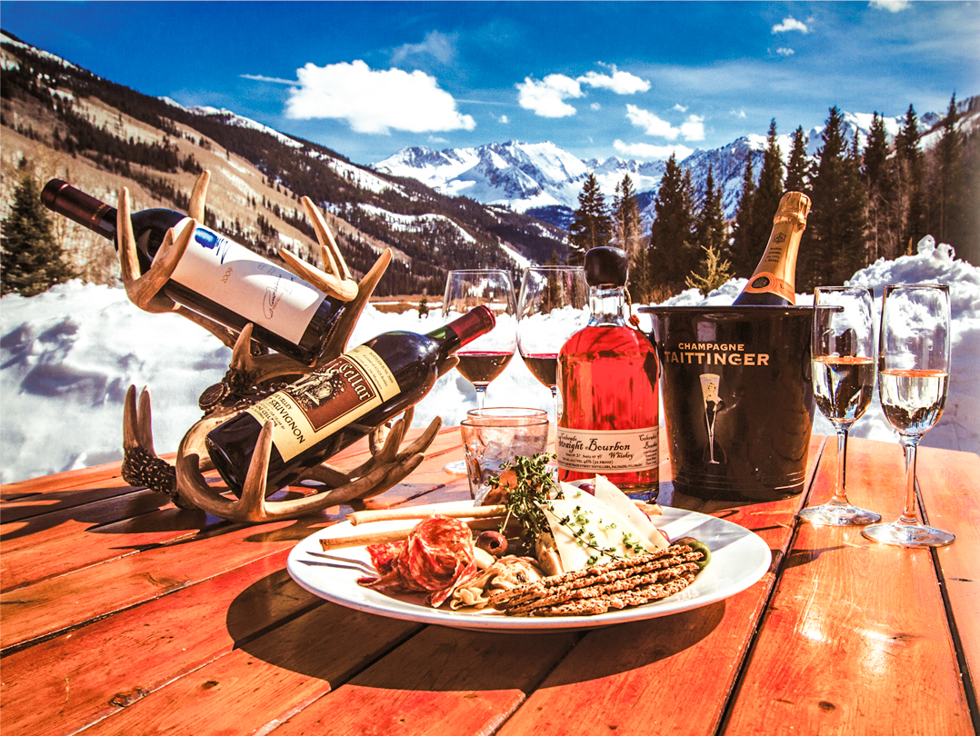 Wine and a chef's plate set on a Pine Creek Cookhouse table with the Elk Mountains beyond.